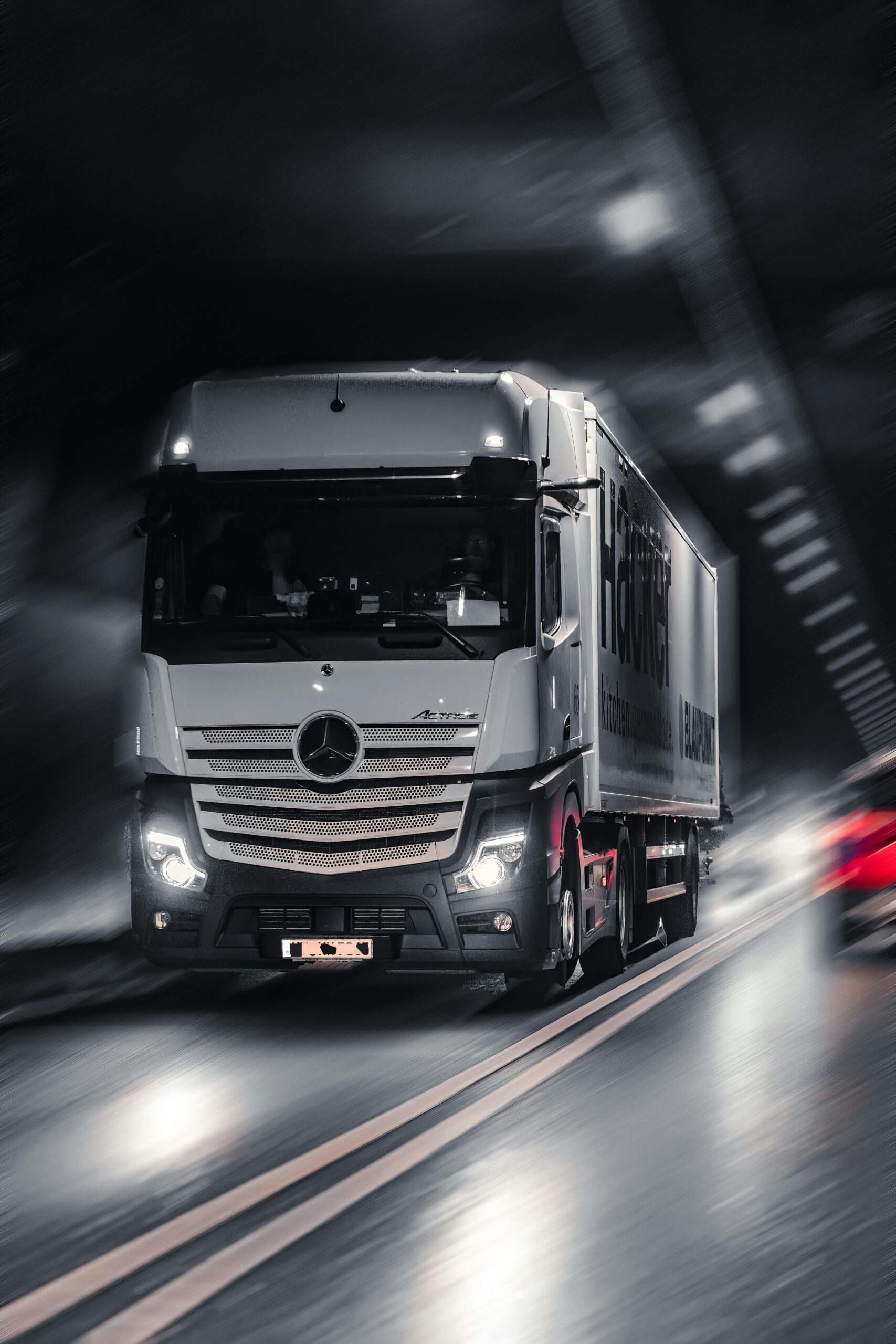 Mercedes-Benz Actros truck speeding through a city tunnel, capturing urban motion and energy.